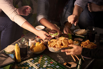Friends gathering to share fries, corn, and burgers with scrabble