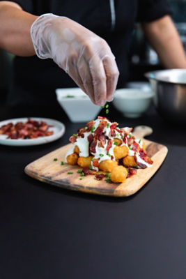 Chef garnishing top and loaded tater tots