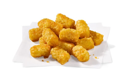 A pile of golden brown tater tots is arranged on overlapping sheets of white paper. The tater tots appear freshly fried, with a crunchy texture and appetizing color. The background is clean and minimal, emphasizing the food's texture and color. No visible text, numbers, or branding is present in the image.