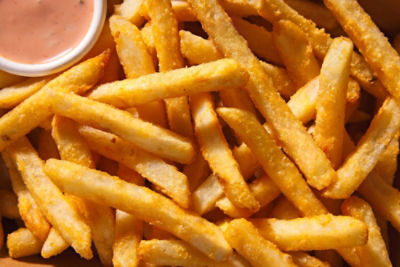 close up of colossal crisp fries with sauce in the corner