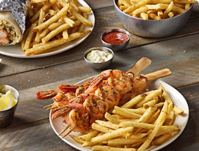 Seasoned fries plated with shrimp, burrito, and dipping sauces