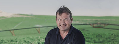 Ted - farmer in sitting in a potato field with irrigation sprinklers in the background